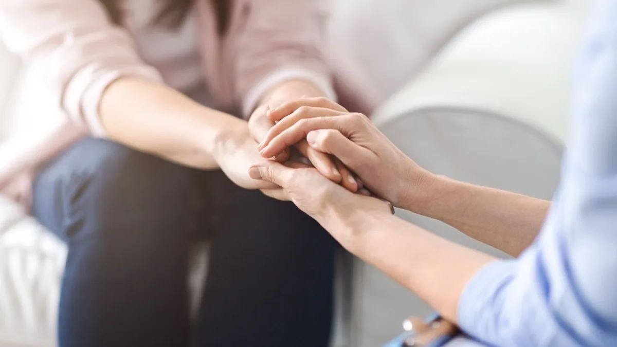 A person gently holds another person's hands.