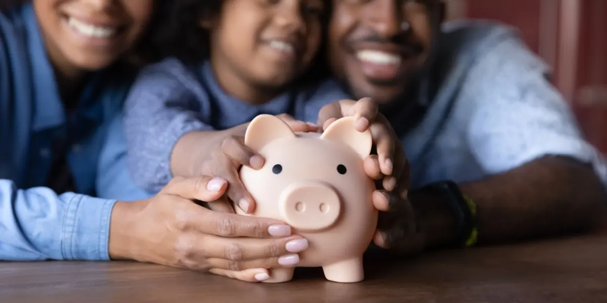 A child and adults gather around a piggy bank.