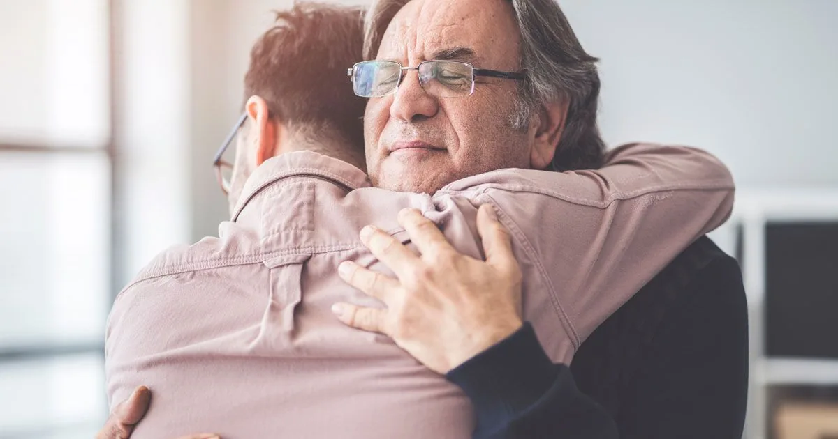 An older adult shares a reassuring hug at home.