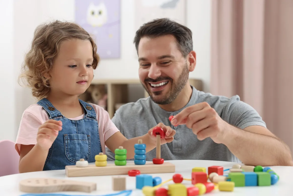 A father and young child explore colorful wooden learning toys together.