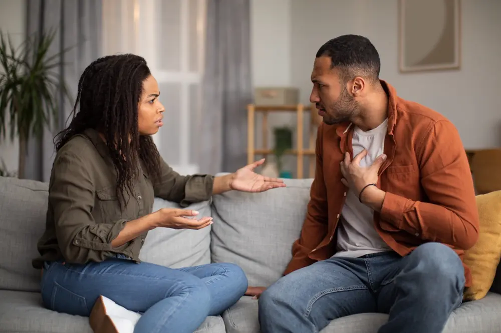 A couple has a serious conversation on a sofa.